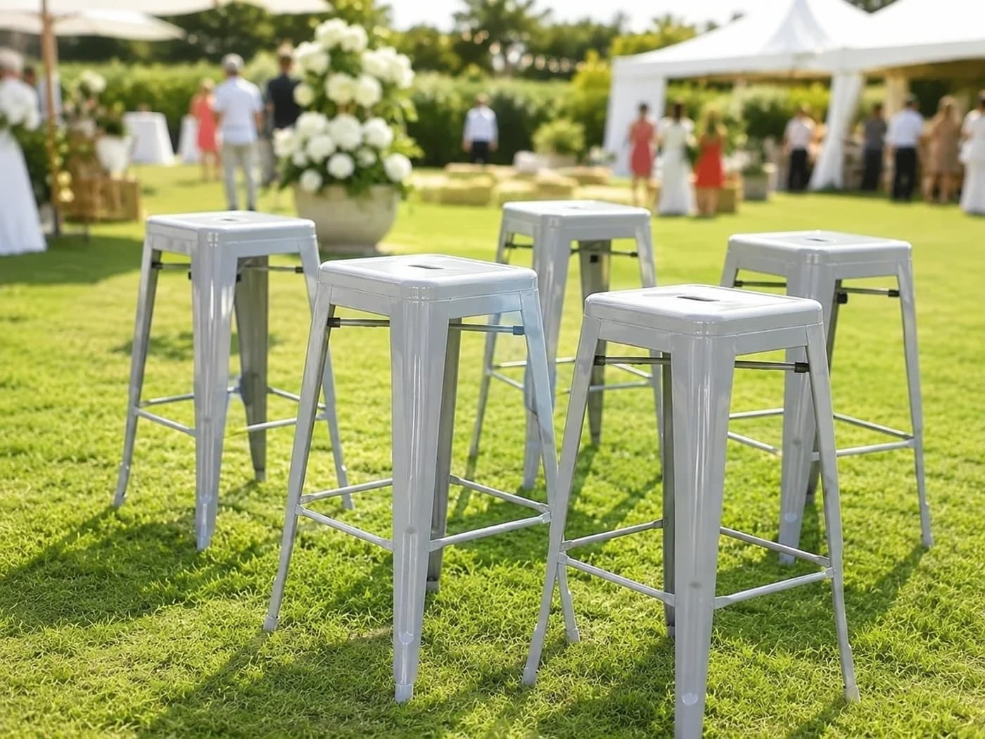 Grey metal bar stools arranged on a lawn for a daytime outdoor event